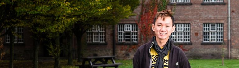 Student stood in front of halls of residence at The University of Manchester